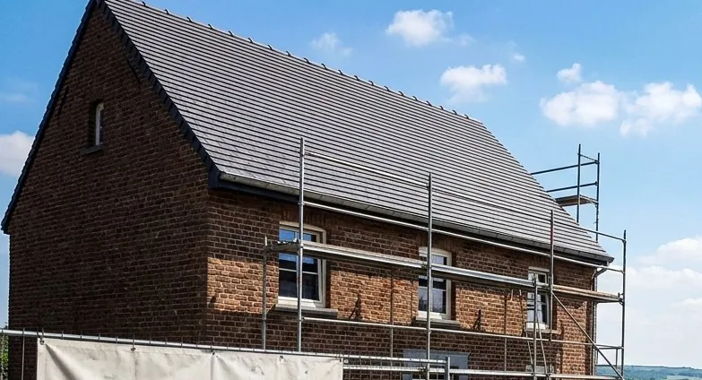 Toiture en ardoises neuves sur une maison en briques, échafaudage encore en place